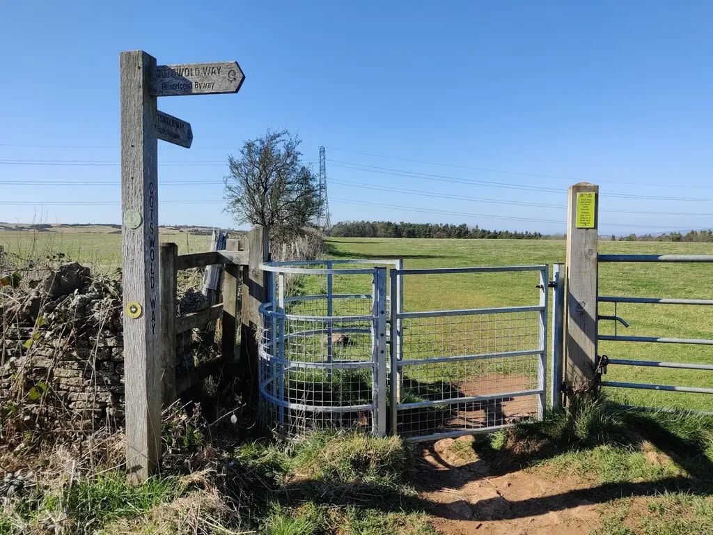 Kissing gate on the Cotswold Way with a footpath stretching across open fields